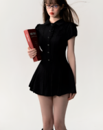 Model wearing the Literature Girl Mini Dress, a black academic aesthetic dress with ruffled details and a book.
