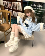 Young woman wearing a blue jojifuku hoodie, thigh-high socks, and boots.