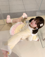 Jojifuku hoodie worn by a person in a retail setting, featuring a yellow long-sleeve top and layered accessories.