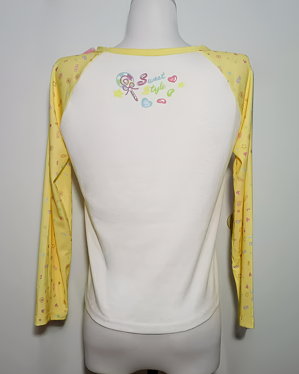 Back view of a yellow Mezzo Piano cake T-shirt with long sleeves, featuring a colorful graphic print and contrasting white underlayer.