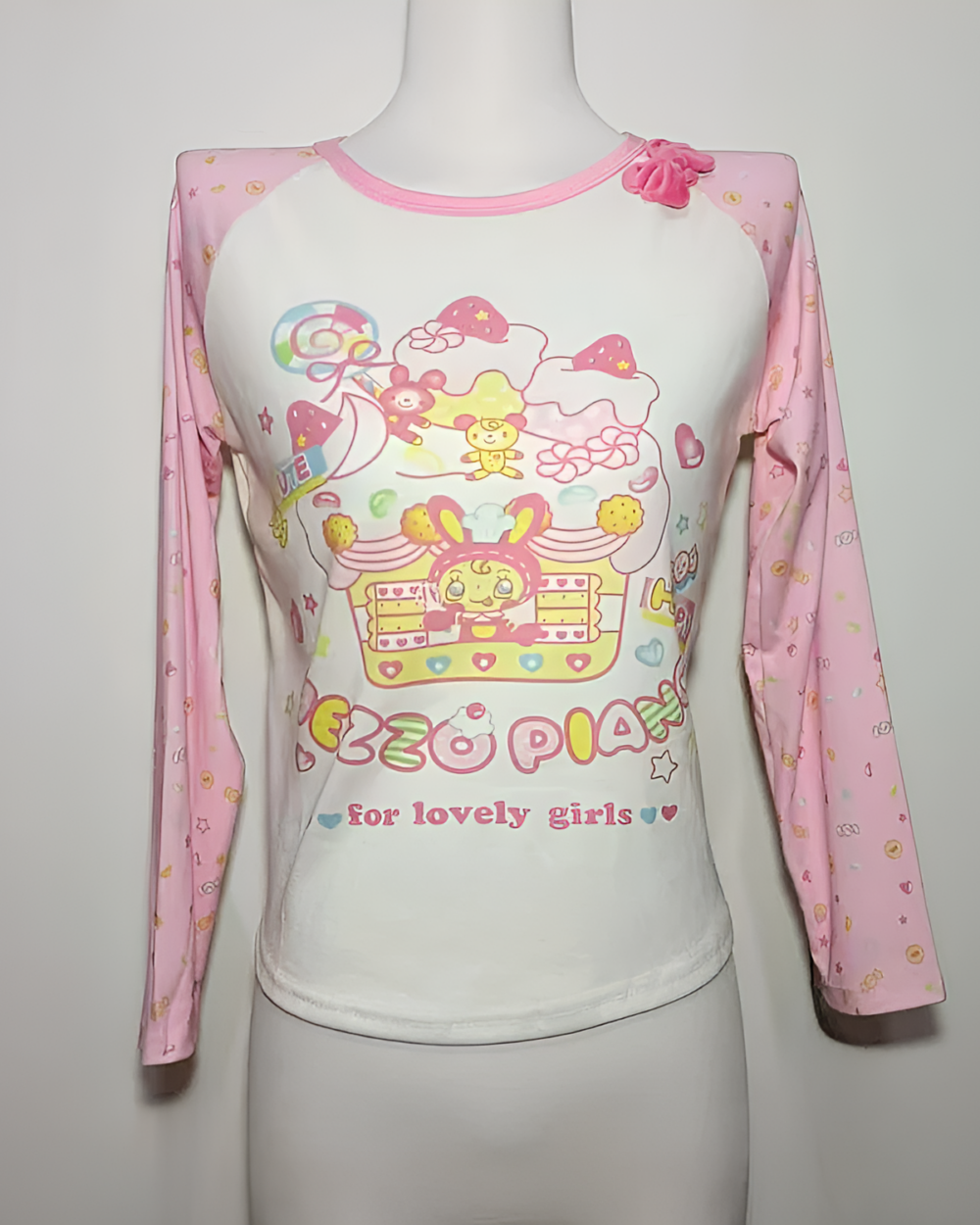 Mezzo Piano cake T-shirt with long sleeves. Features a pink and white design with cartoon cake and character graphics.