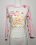 Mezzo Piano cake T-shirt with long sleeves. Features a pink and white design with cartoon cake and character graphics.