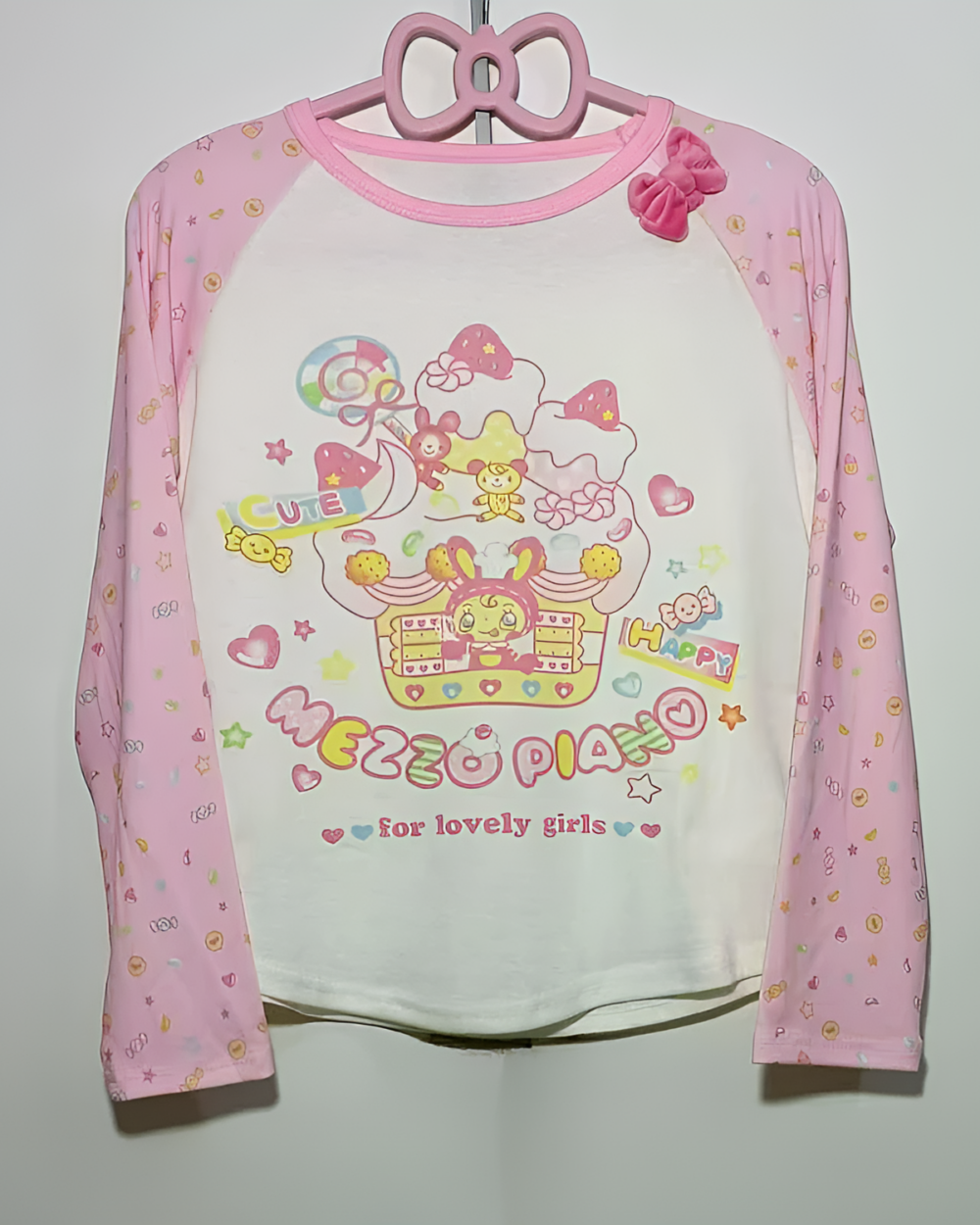 Pink long sleeve Mezzo Piano cake T-shirt with a cute graphic print, hanging on a pink hanger.