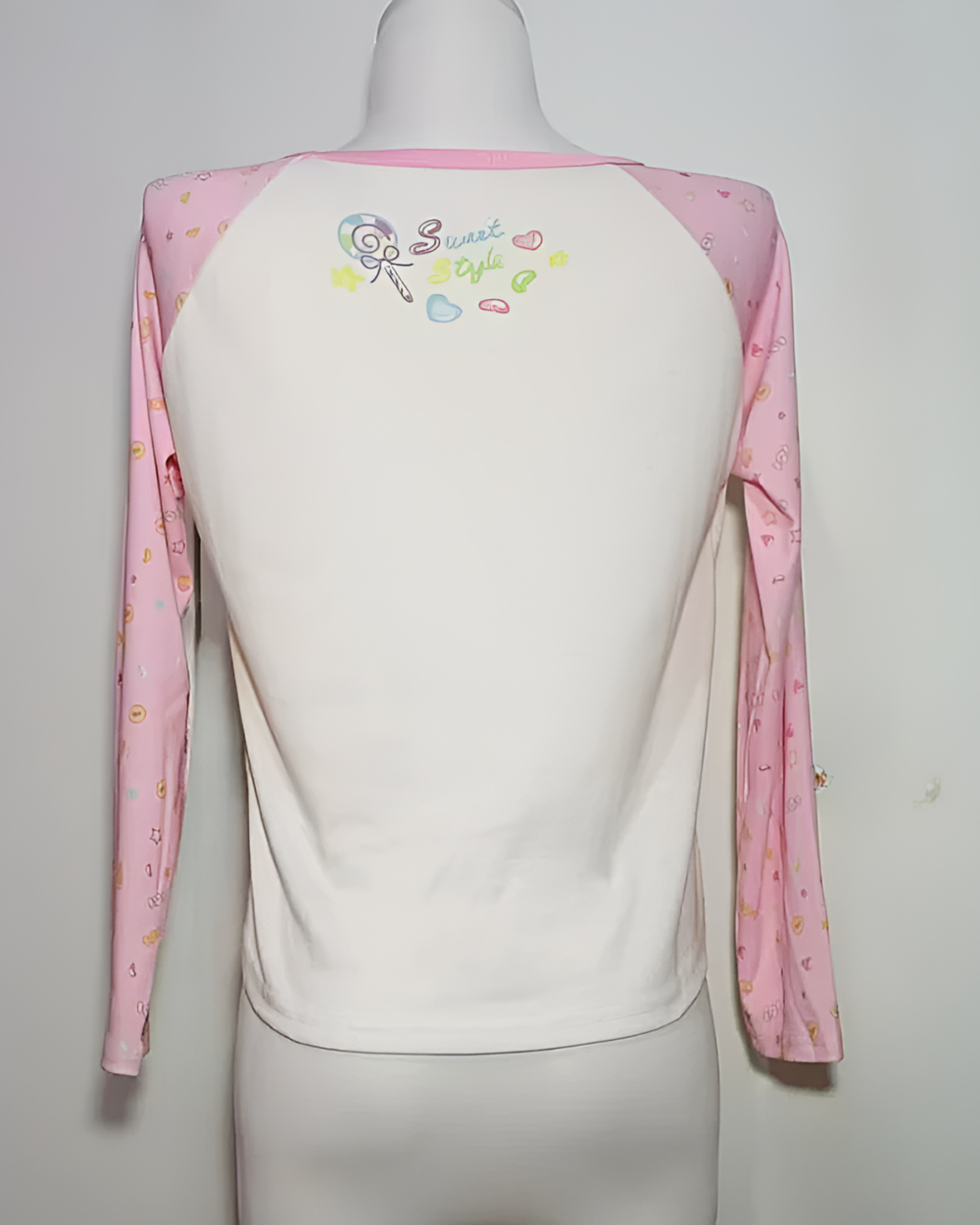 Back view of a Mezzo Piano cake T-shirt, long sleeve, pink and white with colorful graphic details.