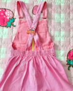 Pink and white gingham Mezzo Piano dress with strawberry embroidery. Features adjustable straps and a flared skirt.