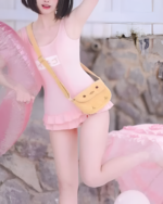Model wearing a pink animecore swimsuit with a yellow bag and inflatable ring. The swimsuit has ruffle details.