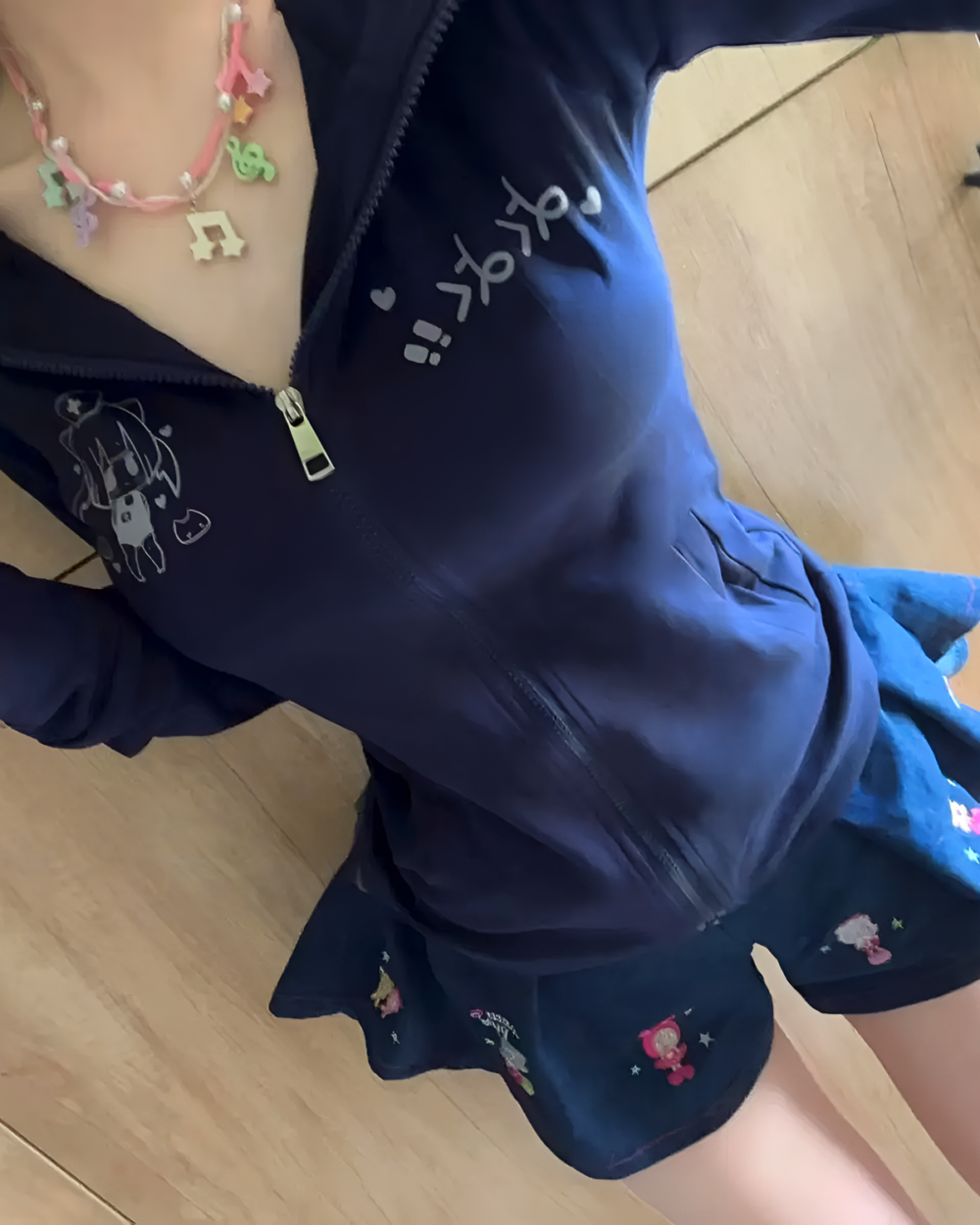 Close-up of a black Yami Kawaii hoodie with a cat graphic and a zipped front, worn with a short skirt.
