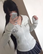Person wearing a grey zip-up Yami Kawaii hoodie with graphics, posing for a selfie. The hoodie features a cute design.