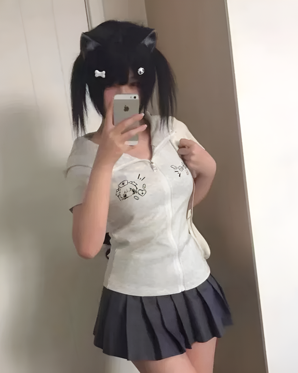 Woman modeling a white outfit with a black skirt and holding a phone, showcasing the style that complements a Yami Kawaii hoodie.