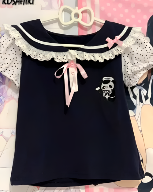Midnight Panda Sailor Tee, a black kawaii t-shirt with a panda sailor illustration and ruffled trim. Features a pink bow detail.