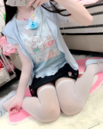 A person wearing a blue Necolon T-Shirt featuring kawaii characters and accessories.