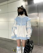 Model wearing a Neko Frill Zip Hoodie in a pastel goth aesthetic. The hoodie features frills and a zip-up design.