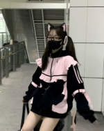 A woman wearing a Neko Frill Zip Hoodie in pastel goth aesthetic, with cat ears and mask. Black and pink zip-up jacket.