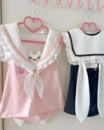 Two Neko Sailor Tee hanging on pink heart-shaped hangers. Pink and navy blue sleeveless tops with a sailor collar and cat ears.