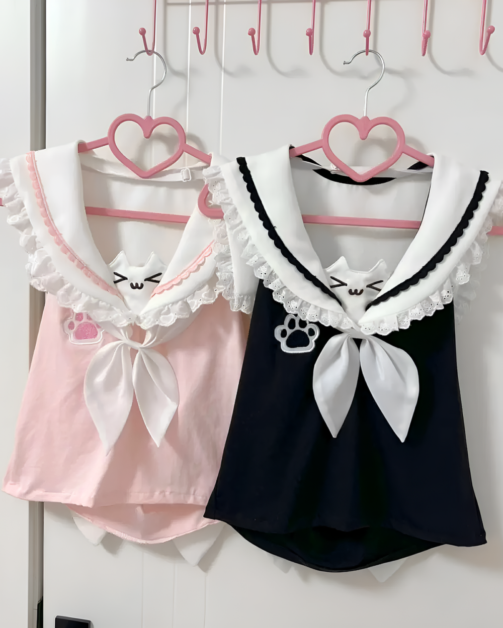 Two Neko Sailor Tee hanging on a rack; pink and black sleeveless tops with a sailor collar and cat paw detail.
