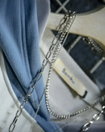 Close-up of a blue Neko Sensei Pullover Hoodie with a silver chain detail on white sneakers.