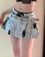 Close-up of a Newspaper Pleated Skirt - Y2K aesthetic, featuring a newspaper print and silver accents.