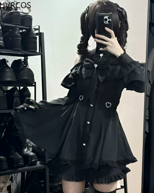 Model wearing a black Noir Heart Ruffle Cold-Shoulder Coord, a Gothic Lolita coord with ruffle details and heart accents.