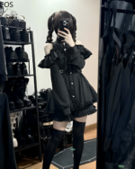 A model wearing the Noir Heart Ruffle Cold-Shoulder Coord, a black Gothic Lolita coord with ruffle details and cold shoulder design.