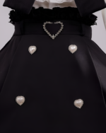 Close-up of Noir Pearl Pinafore Coord details, showcasing pearl buttons and heart accents. Reflects a distinct Jirai Kei aesthetic.