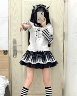 Model wearing the Noir Sonata Skirt, a black and white piano key skirt, with striped socks and a graphic tee.