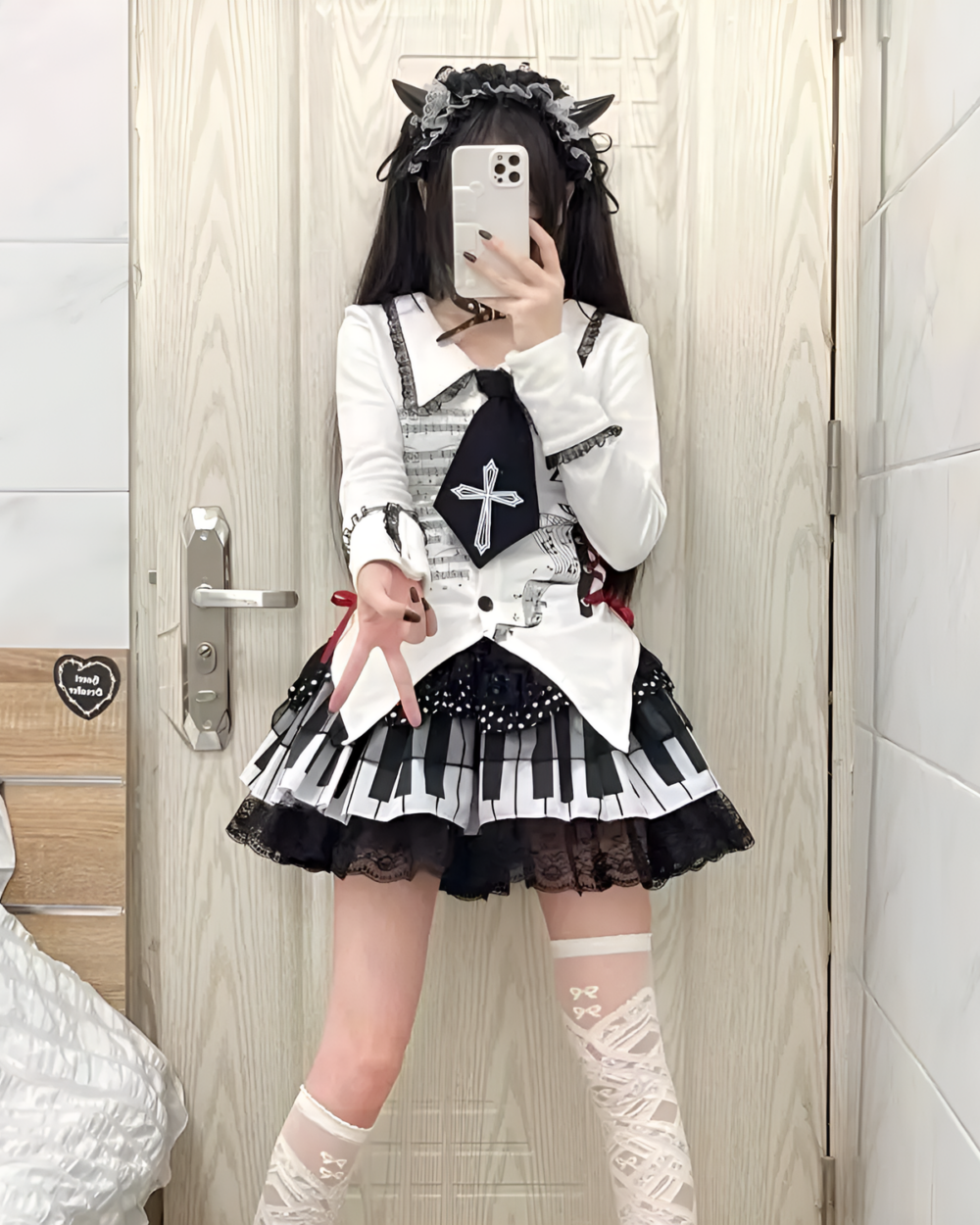 Woman modeling the Noir Sonata Skirt, a black and white piano key skirt, with a white long-sleeve top and lace socks.