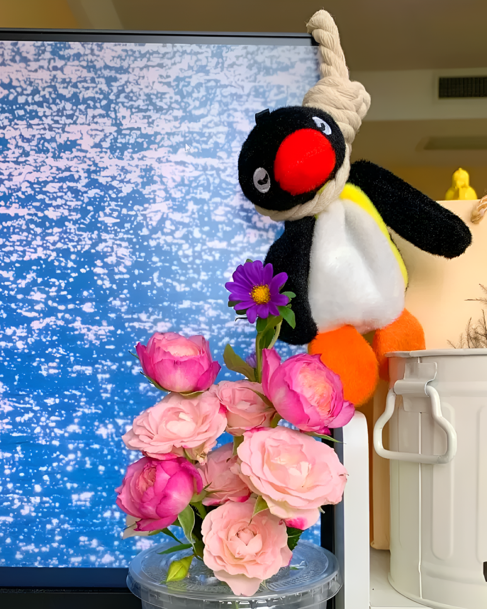 Close-up of a Noosed Penguin Keychain with flowers. Features a black and white plush penguin with a red beak.