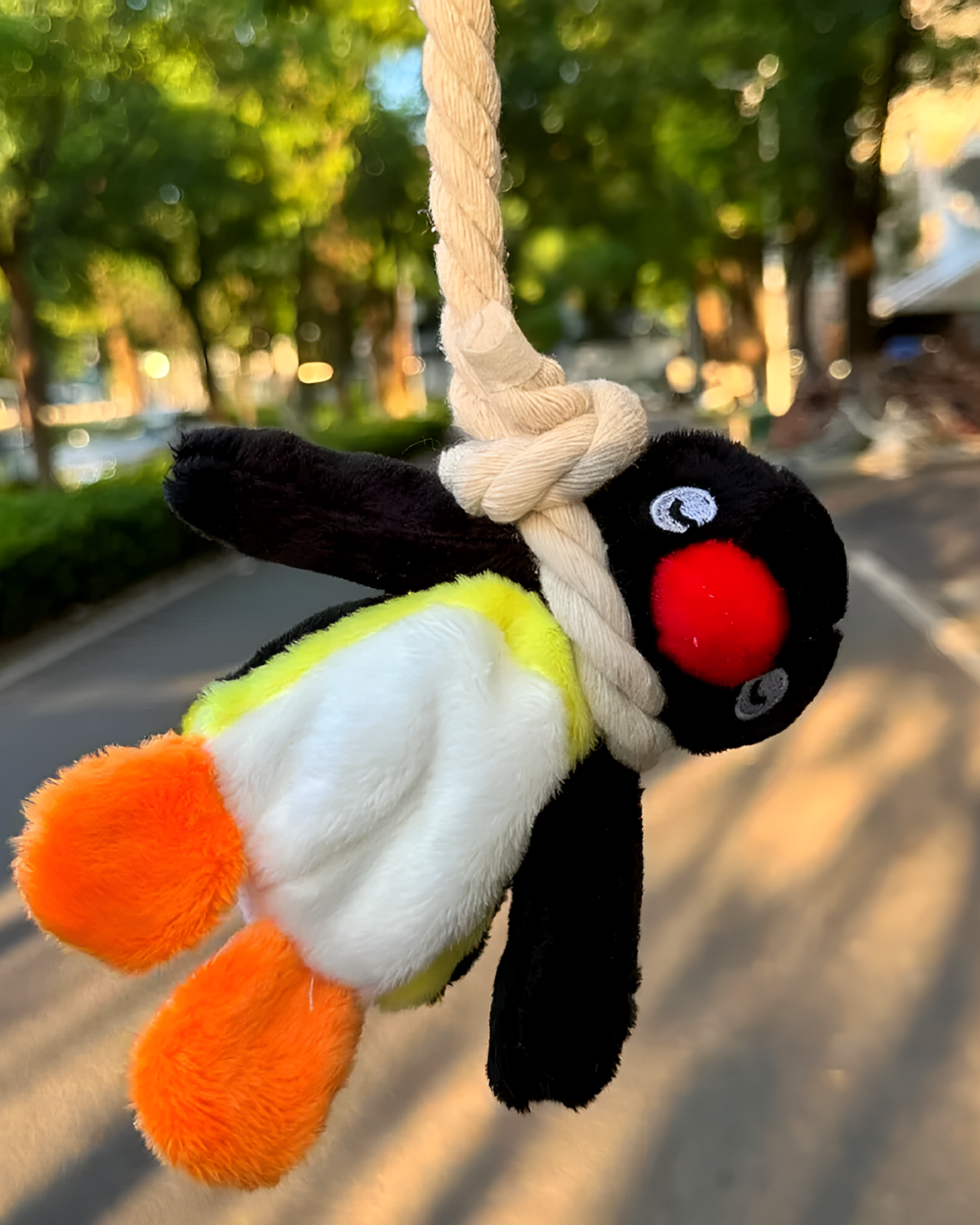 Close-up of a Noosed Penguin Keychain with a black and white plush penguin hanging from a rope.