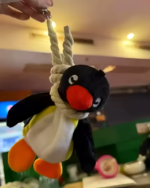 Close-up of a Noosed Penguin Keychain, featuring a plush penguin with a rope noose.