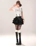 Model wearing a black Obsidian Star-Chain Mini Skirt with a white top and black boots. The skirt features a layered design and star details, part of the star chain skirt collection.