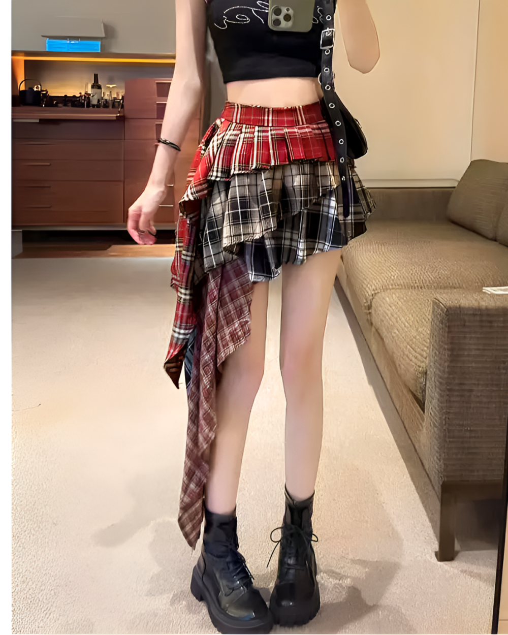 Woman wearing a patched pleated skirt with a grunge aesthetic. Red and black plaid skirt with mismatched panels.