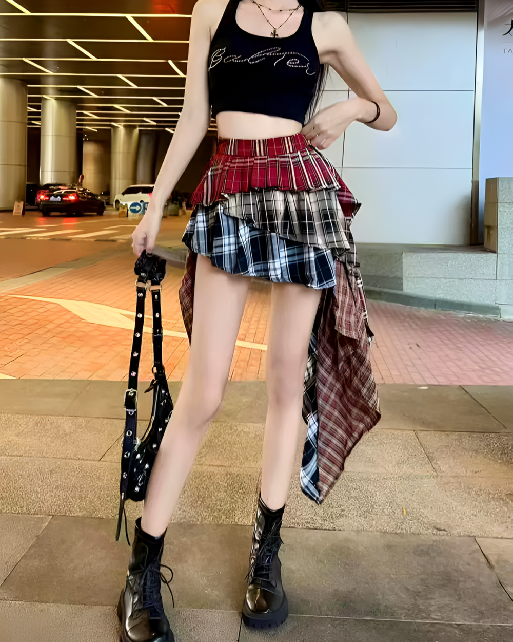 Woman wearing a patched pleated skirt with a plaid pattern and black boots. Grunge aesthetic fashion.