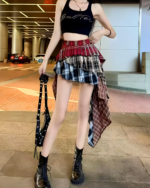 Woman wearing a patched pleated skirt with a plaid pattern and black boots. Grunge aesthetic fashion.