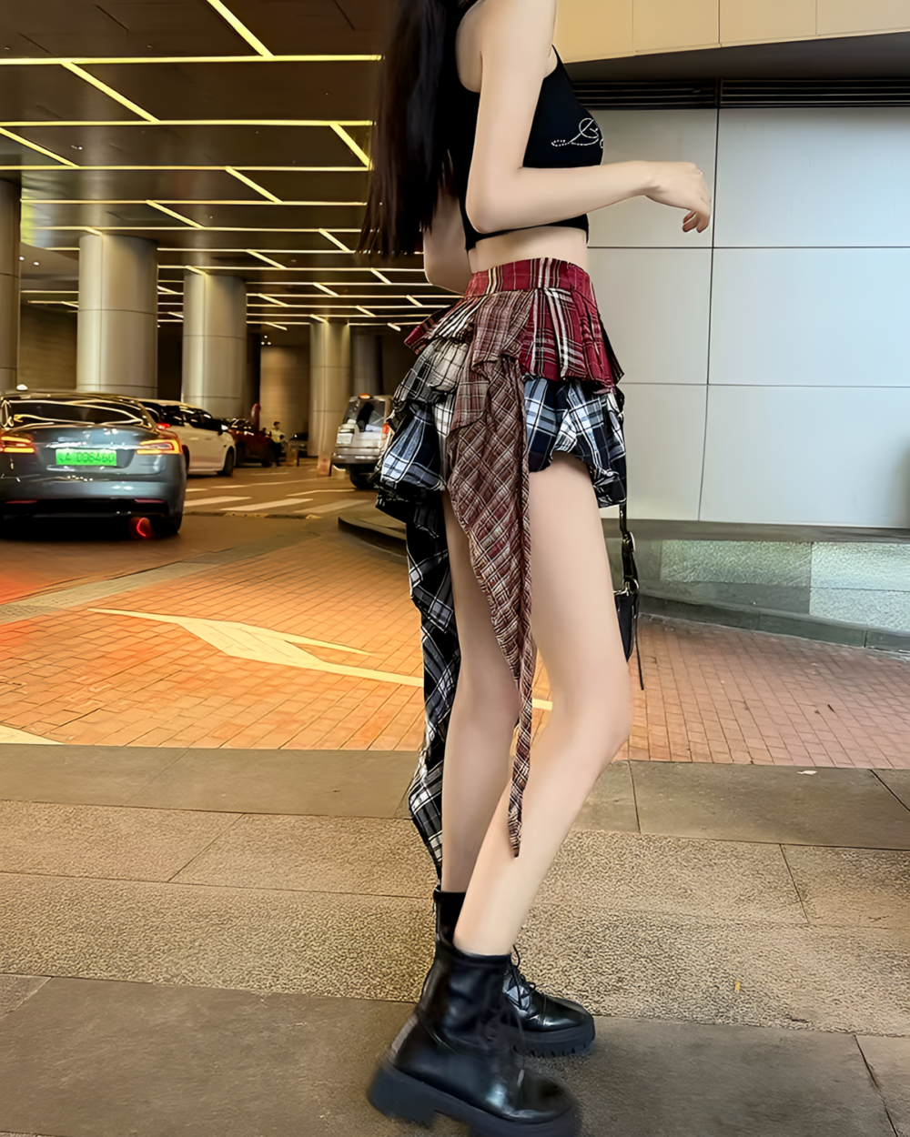 Woman wearing a patched pleated skirt with a grunge aesthetic, paired with a black top and boots. A fashionable layered skirt.