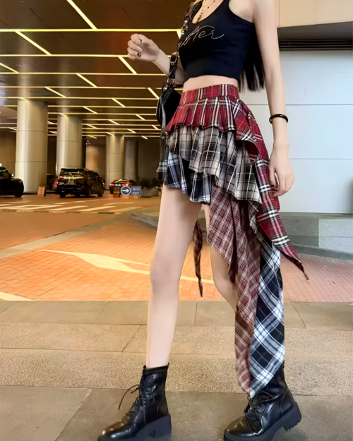 Model wearing a grunge aesthetic outfit with a red and black patched pleated skirt and chunky boots.