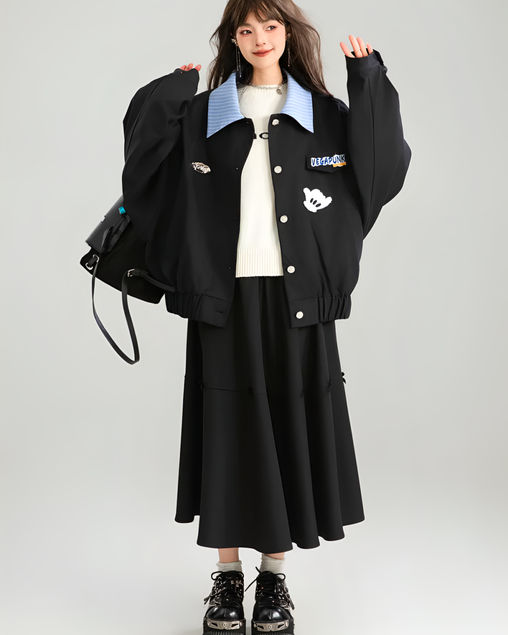 Model wearing a black Patchy Jacket with colorful embroidered patches. Preppy aesthetic oversized fit jacket.
