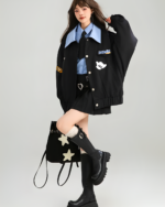 Woman wearing a black Patchy Jacket with colorful patches, styled with knee-high boots and a plaid skirt for a preppy aesthetic.