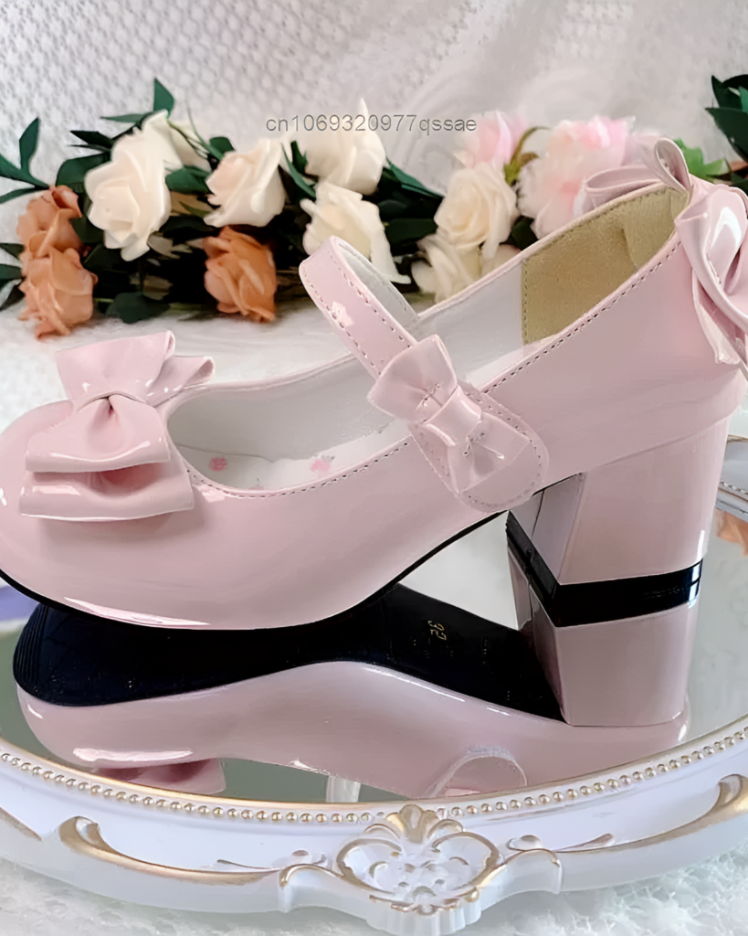 Pink Petal Block-Heel Mary Janes with a bow detail, shown on a decorative surface. Features a block heel and rounded toe.