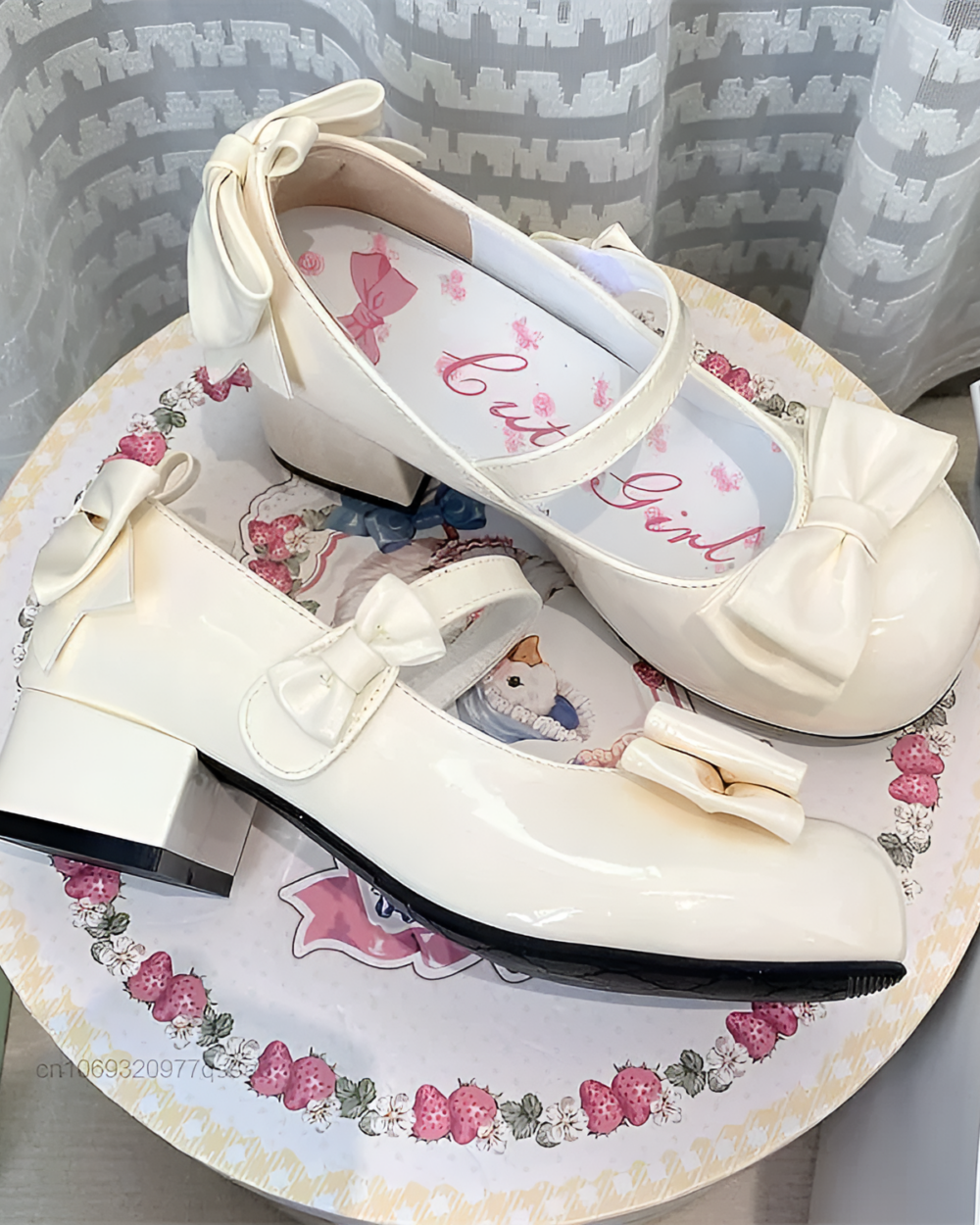 Close-up of white Petal Block-Heel Mary Janes with a bow detail and a block heel. The shoes are on a patterned surface.