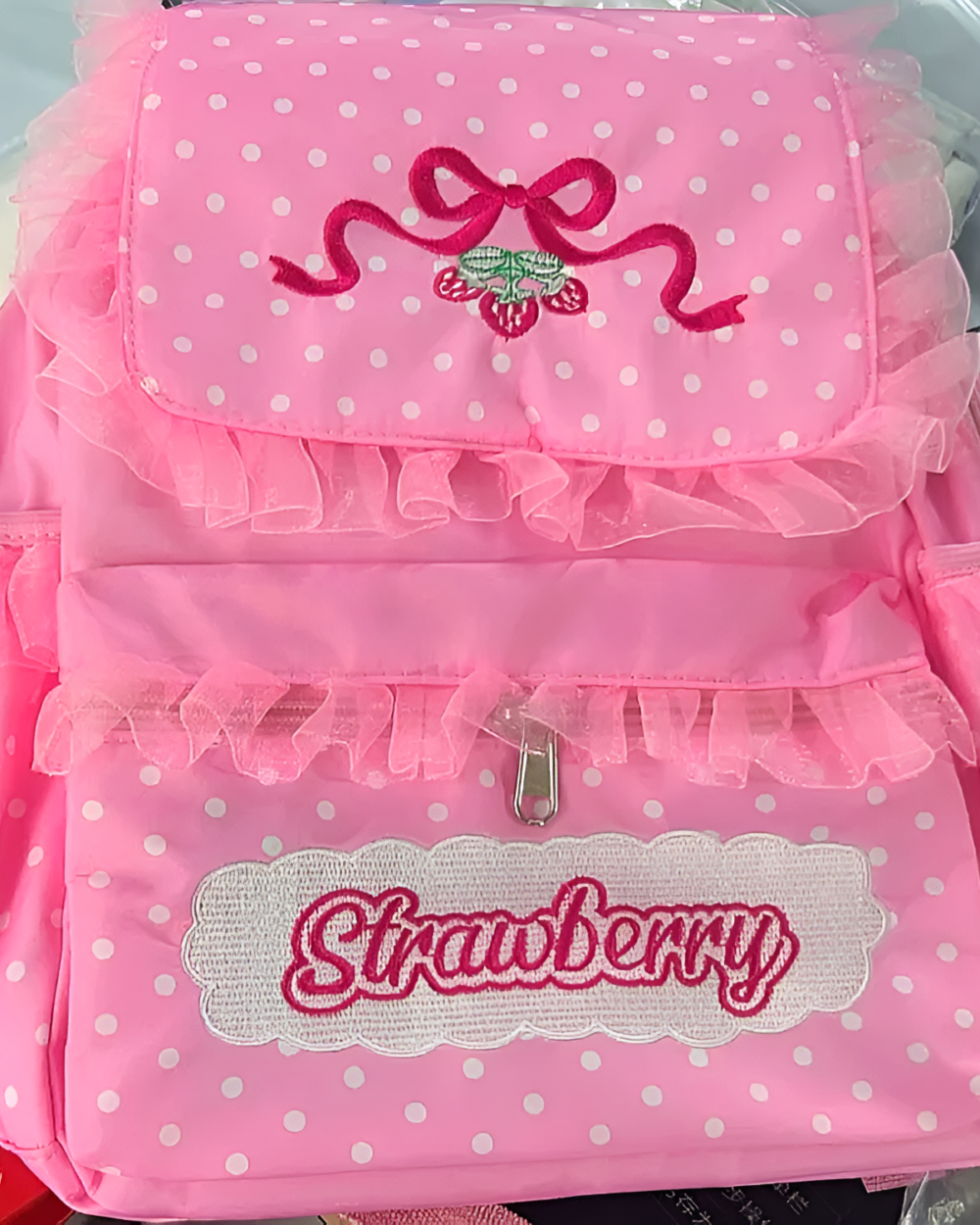 Pink strawberry backpack featuring a strawberry embroidery and polka dot design.