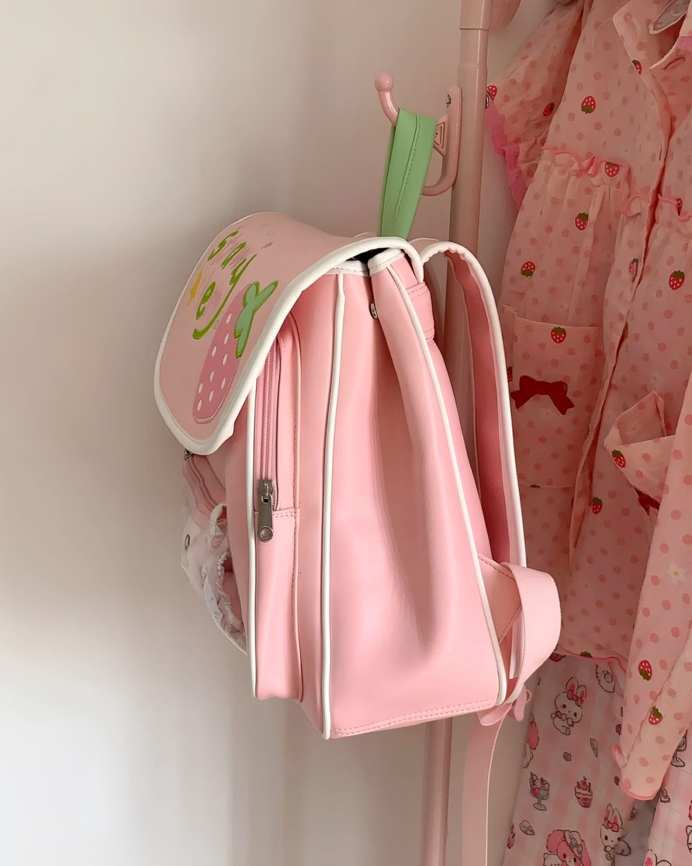 Pink strawberry ita bag hanging on a closet rod.