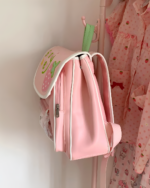 Pink strawberry ita bag hanging on a closet rod.