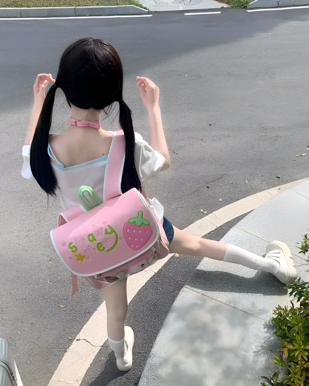 Pink strawberry ita bag worn by a young girl on a street.