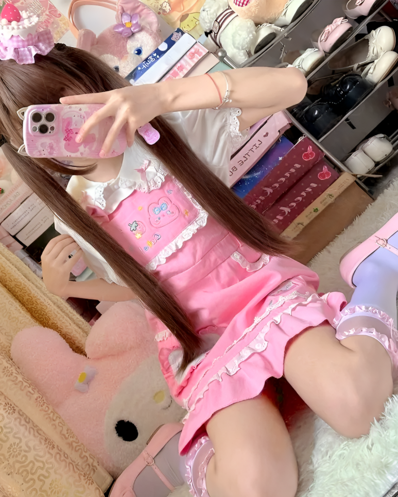 Close-up of a woman wearing a pink strawberry mini dress by Jojifuku, featuring a ruffled hem.