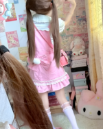 Model wearing a pink strawberry mini dress by Jojifuku. Aesthetically pleasing, with ruffles and lace details.