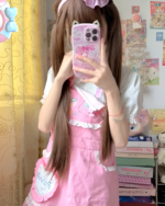 Woman wearing a pink strawberry mini dress by Jojifuku. The aesthetic dress features ruffle details.