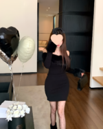 Woman wearing a black Plush Christmas Dress with long sleeves, near balloons and a gift box.