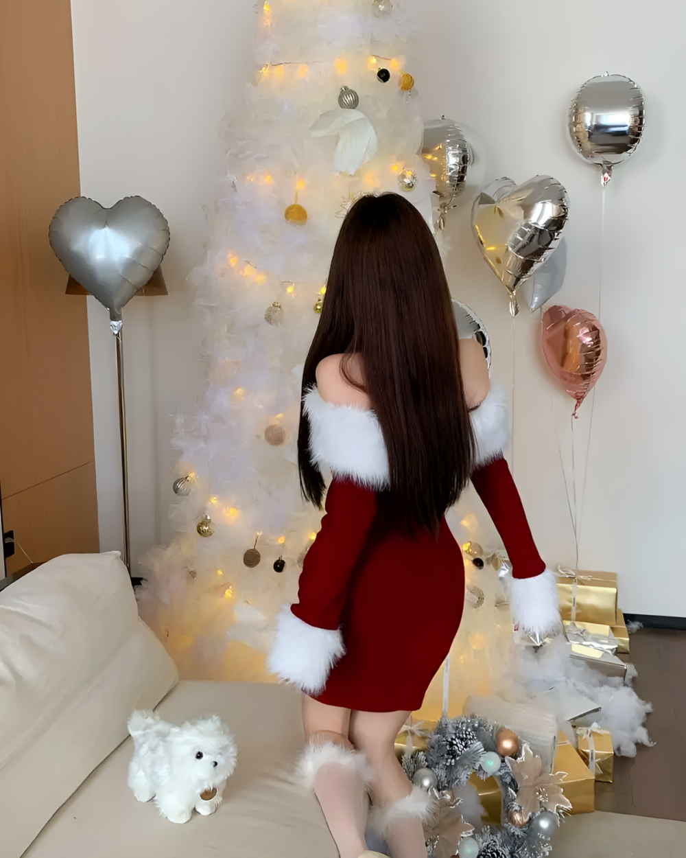 Woman wearing a red Plush Christmas Dress with white faux fur sleeves, with festive decorations and balloons.