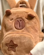 Close-up of a brown Capybara plushie bag with a star embroidery and facial details.