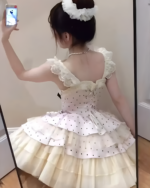 Woman wearing a white polka dot Hime Lolita dress with ruffled details, seen from the back in a mirror.